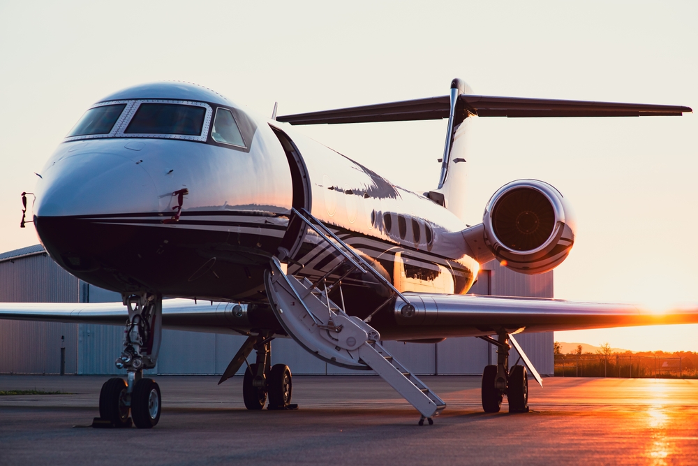 A private jet parked on the ramp at sunrise with the boarding stairs down, waiting for a chartered departure.