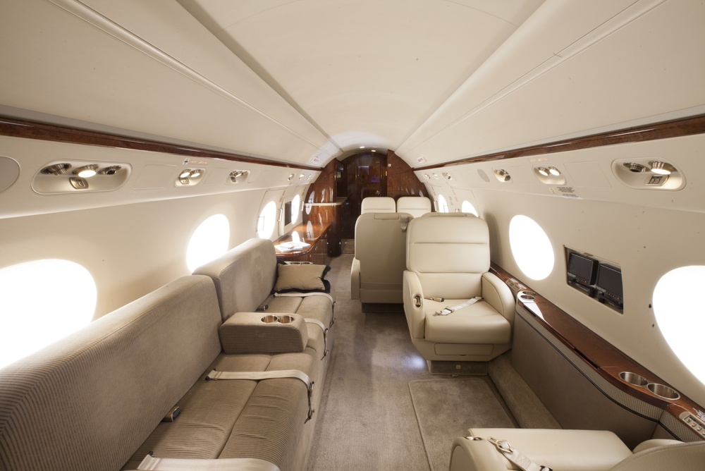 The cabin of a private jet with leather seating and wooden tables, configured for a chartered flight operated under Part 135.