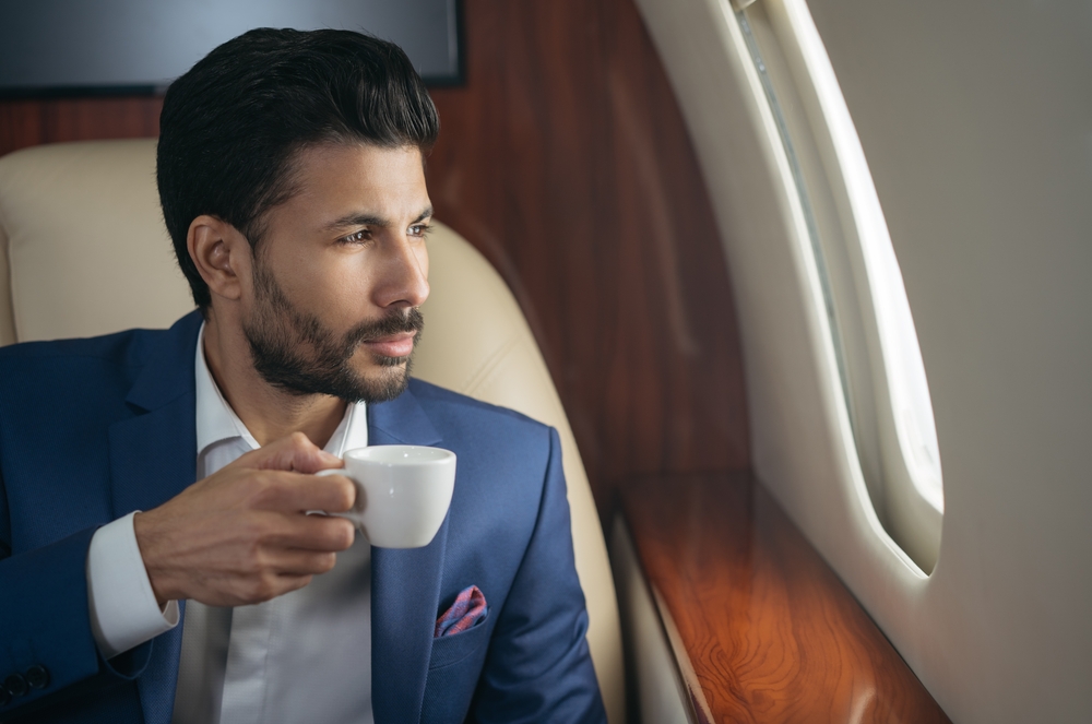 A businessman working with a coffee in the cabin of a private jet after a commercial flight cancellation.