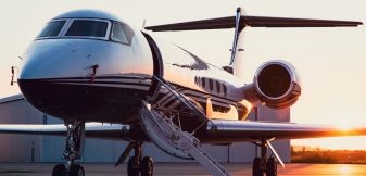 A private jet parked on the ramp at sunrise with the boarding stairs down, waiting for a chartered departure.