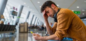 A stranded traveler on his phone in an airport terminal after his flight was canceled.